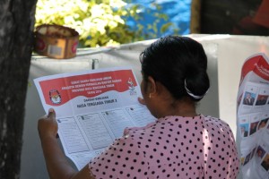 Pemilih sedang memperhatikan kartu suara di salah satu TPS di Sumba Timur NTT